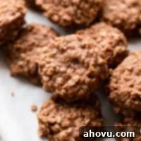 Several classic no-bake cookies, featuring peanut butter, chocolate, and oats, arranged neatly on a piece of parchment paper, ready to be served.