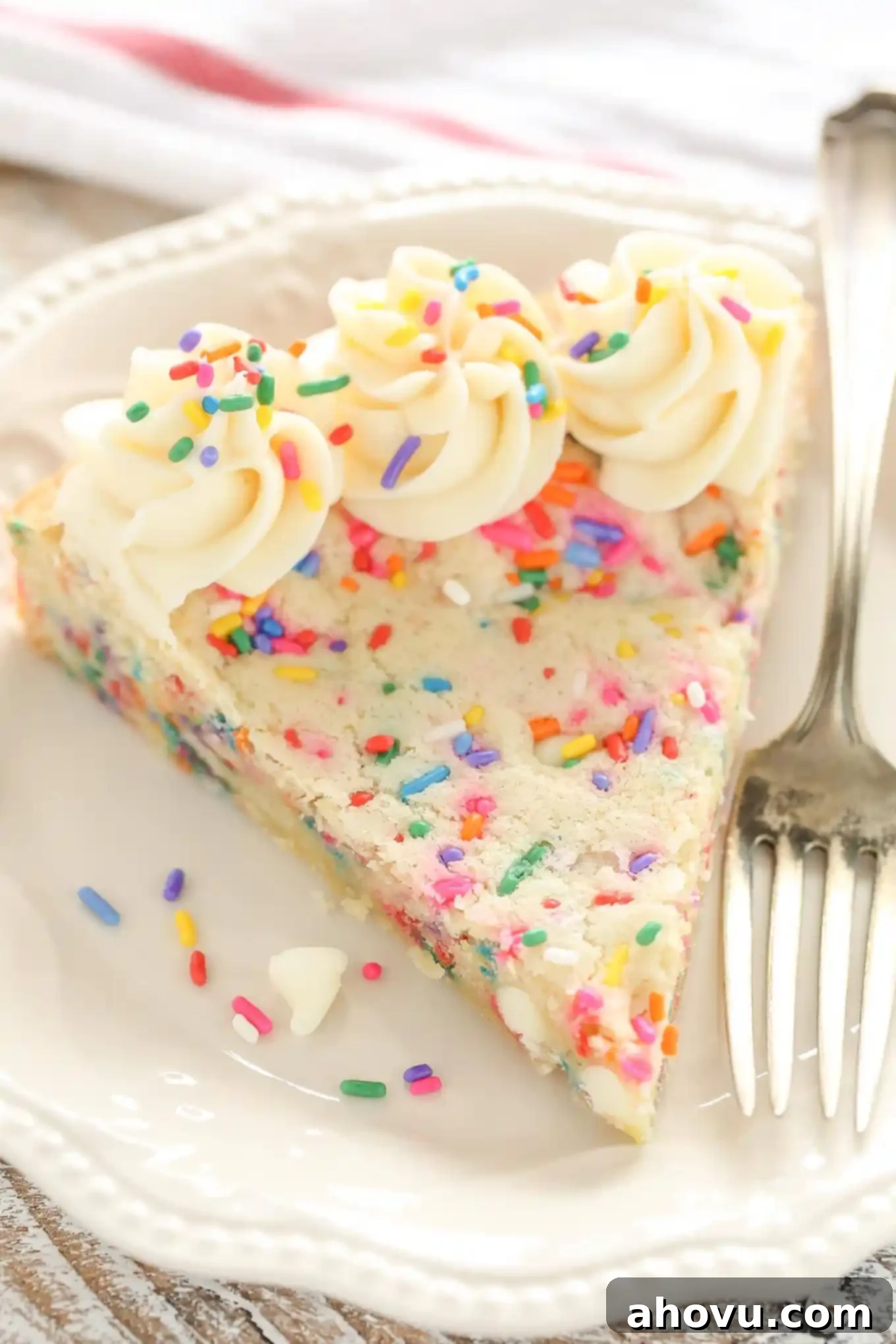 A slice of funfetti sugar cookie cake on a white plate with a fork. 