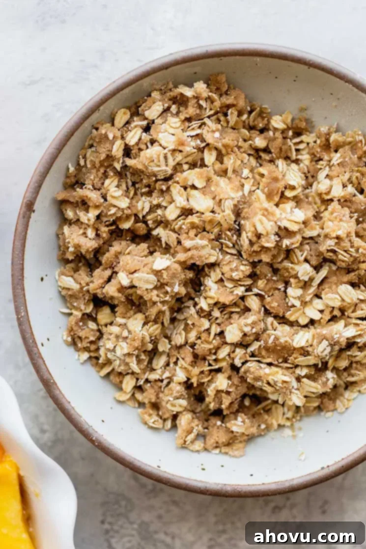 Golden Peach Crumble 4 A white bowl filled with a brown sugar oat topping mixture, ready for the peach crisp.