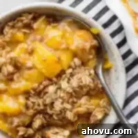 Golden Peach Crumble 7 A bowl of peach crisp with a spoon in it.