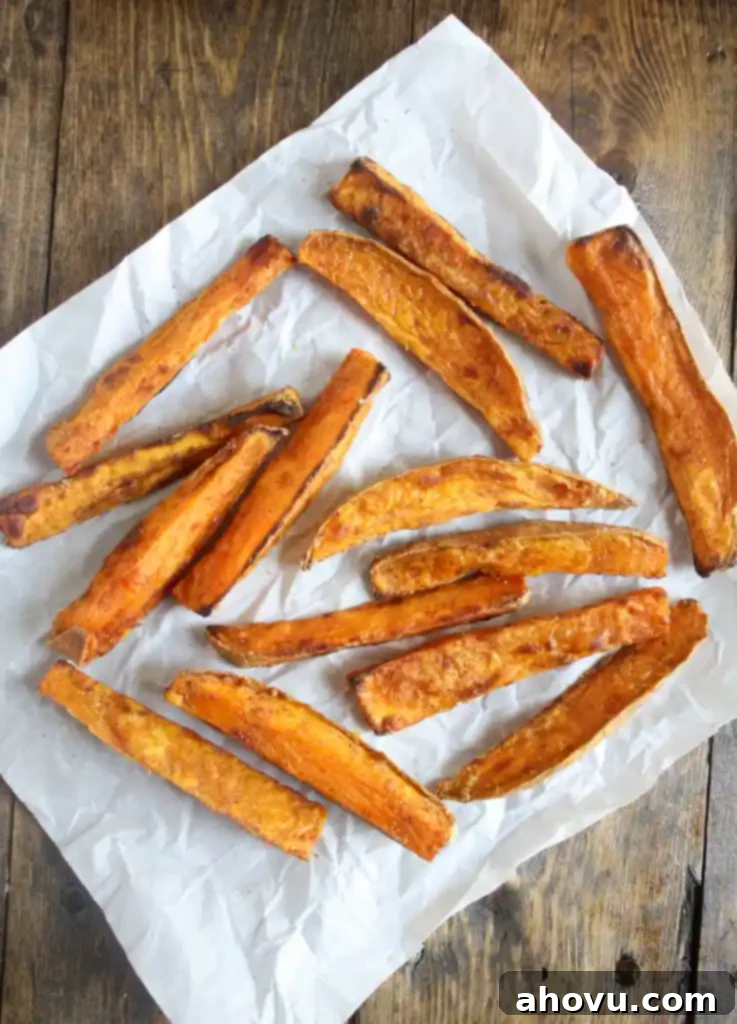 Overhead view of oven baked sweet potato fries on a square of parchment paper. 