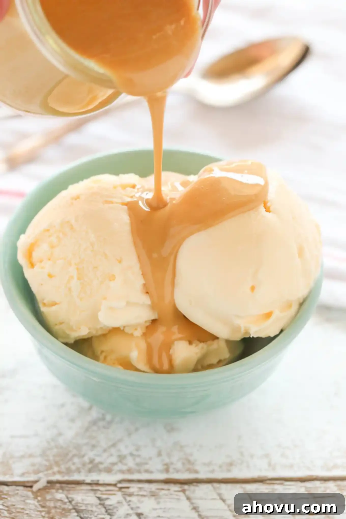 Peanut Butter Crunch Coating 2 A scoop of vanilla ice cream topped with hardening homemade peanut butter magic shell, showcasing its smooth texture and rich color, ready to be enjoyed.