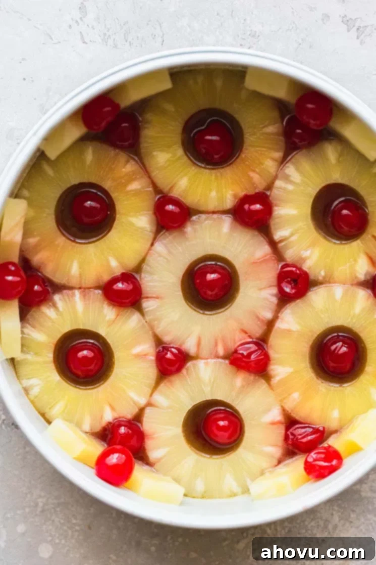 Golden Pineapple Flip Cake 3 A round cake pan lined with pineapple slices, cherries, and the caramelized sugar topping.