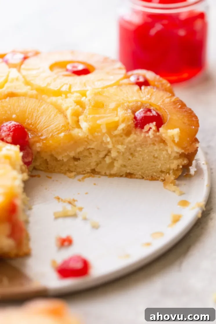 Golden Pineapple Flip Cake 5 A pineapple upside down cake on a plate with one slice taken out to show the texture of the cake.