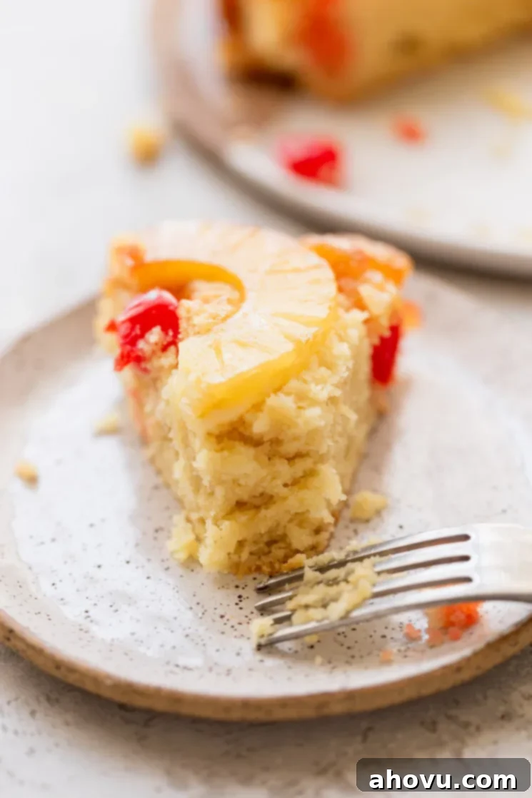 Golden Pineapple Flip Cake 6 A single piece of cake on a plate with a bite taken out of it.