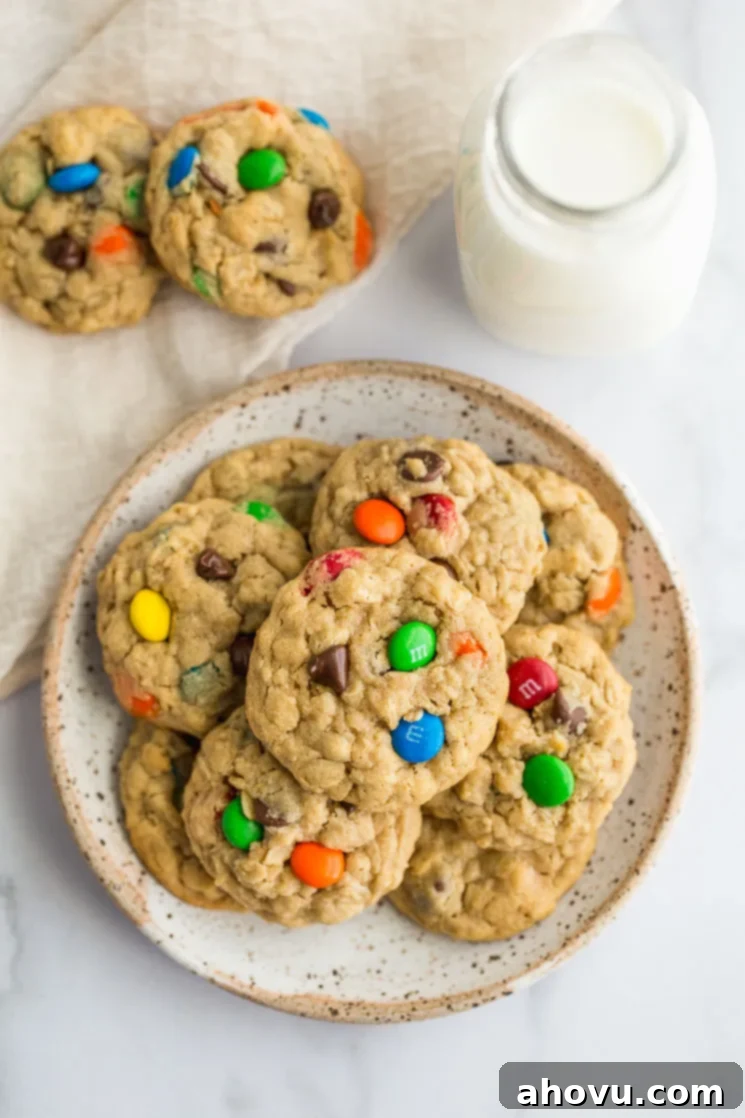 Monster cookies on a plate with more cookies and milk on the side, showcasing their soft, chewy texture.