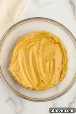 A glass bowl with the wet ingredients for monster cookies mixed together, including butter, sugars, peanut butter, egg, and vanilla.