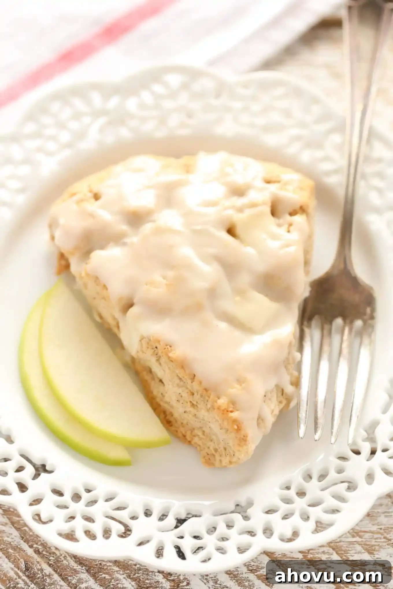 Close up of a single Apple Cinnamon Scone, drizzled with a sweet vanilla glaze, highlighting its soft texture and warm spices.
