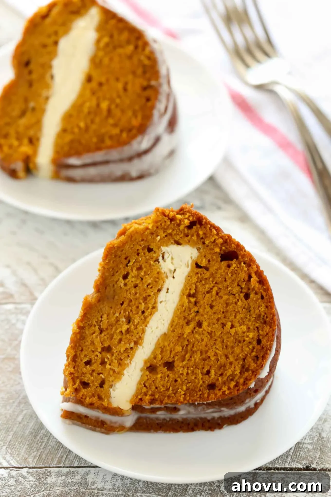 Pumpkin Swirl Cream Cheese Bundt 4 Two generous slices of pumpkin bundt cake, showcasing the distinctive cream cheese layer, served on elegant white plates.