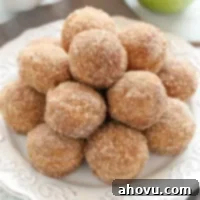 Oven-Fresh Apple Cider Donut Bites 6 A freshly baked apple cider donut hole, glistening with a sugar coating, sits invitingly.