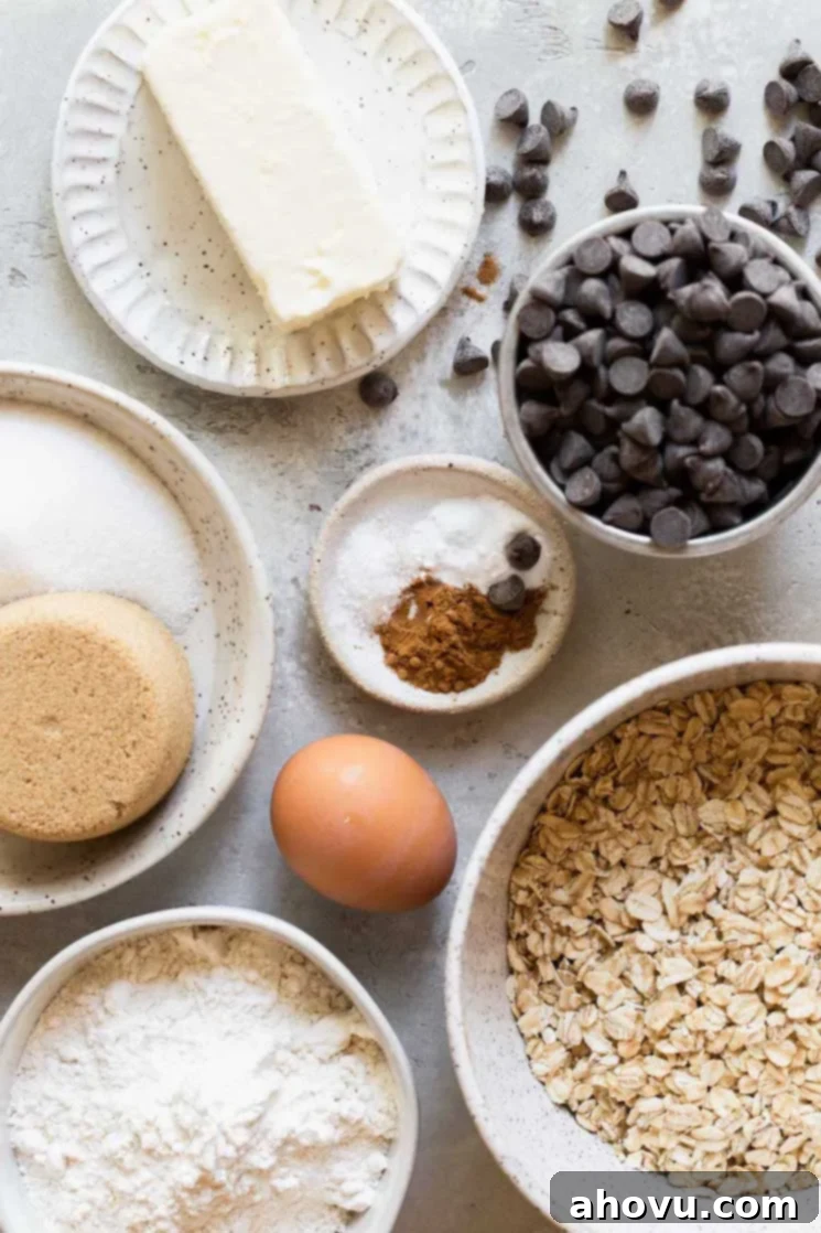 An overhead shot showcasing all the essential ingredients laid out neatly in speckled bowls and on plates, ready for baking soft and chewy oatmeal chocolate chip cookies.