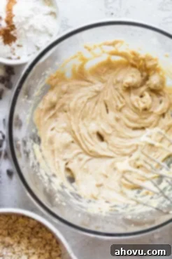 A close-up shot of a mixing bowl containing creamed butter, light brown sugar, granulated sugar, a room-temperature egg, and pure vanilla extract, ready to be fully combined for the cookie dough.
