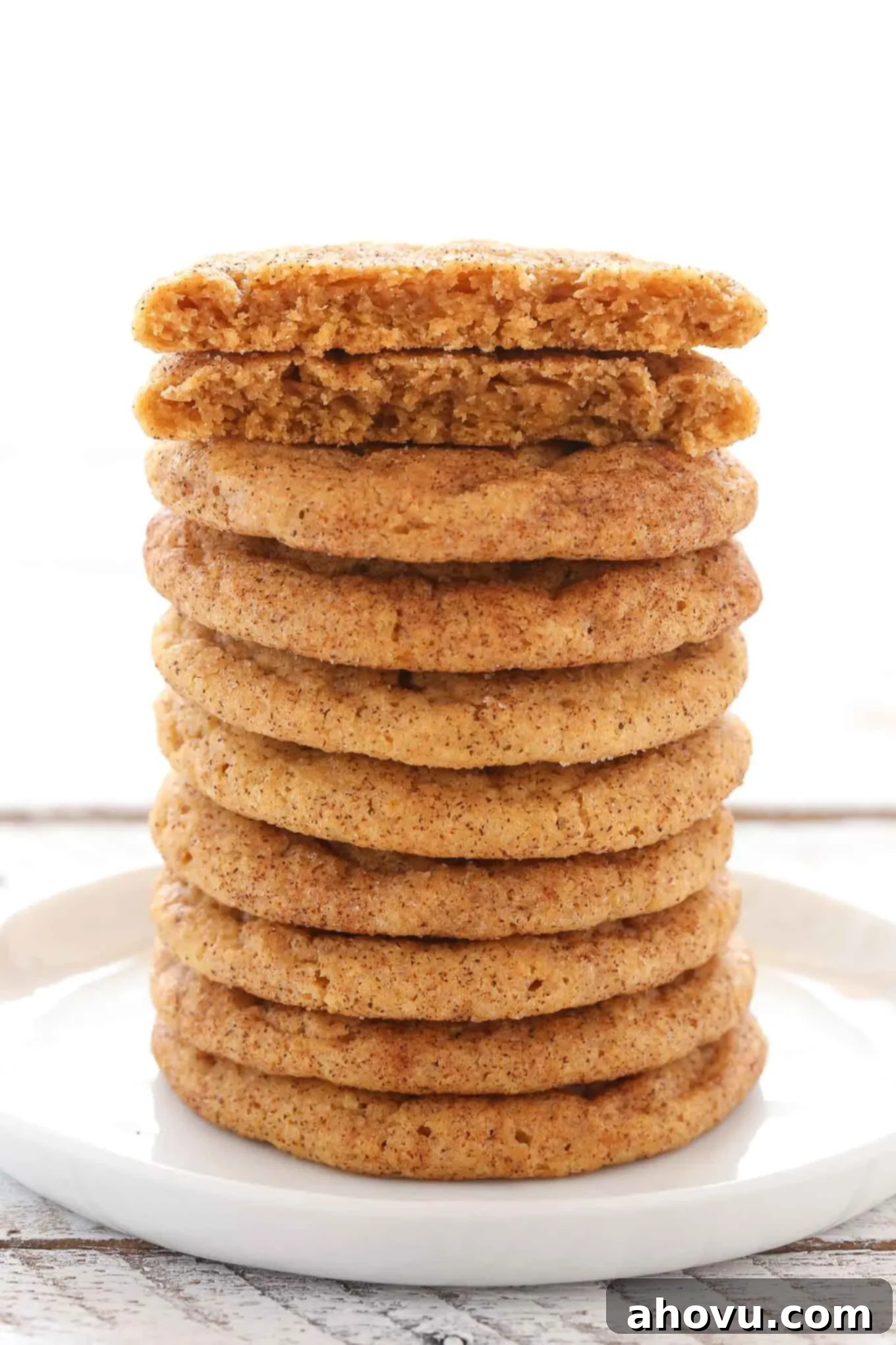 Spiced Pumpkin Snickerdoodles 11 A captivating tall stack of perfectly baked pumpkin snickerdoodles arranged on a white plate, with the top cookie enticingly broken in half to reveal its soft, chewy interior. A true testament to the recipe's success.