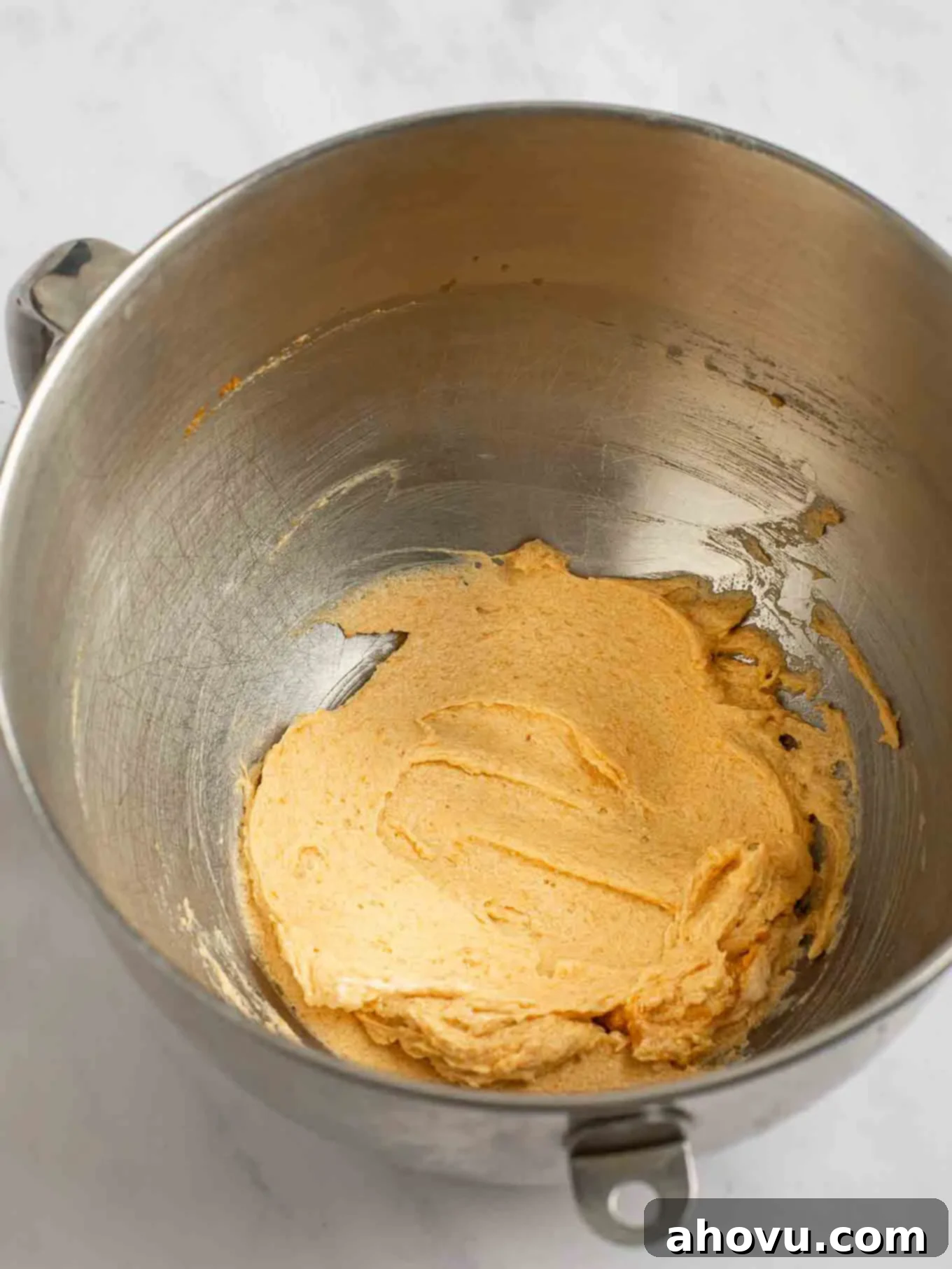 Spiced Pumpkin Snickerdoodles 5 The wet ingredients for pumpkin snickerdoodles, including butter, granulated sugar, brown sugar, egg yolk, vanilla extract, and pumpkin puree, are thoroughly mixed until creamy and smooth in the bowl of a stand mixer.