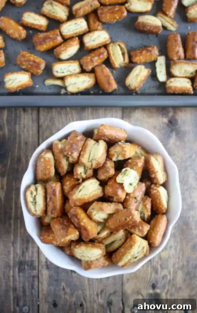 Savory Seasoned Pretzels 4 Overhead view of ranch pretzels in a white bowl next to a baking tray of freshly baked pretzels.