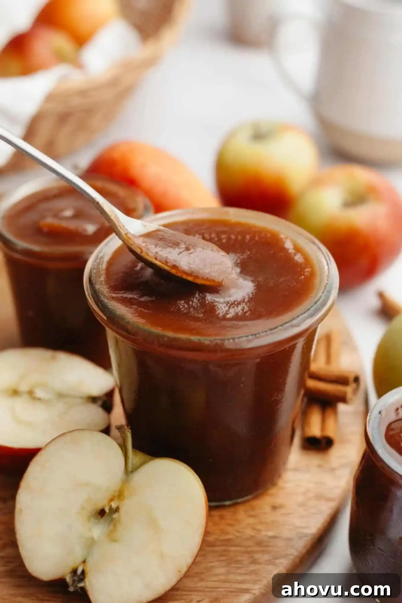 Homemade Spiced Apple Butter 11 A side view of a glass jar of homemade apple butter, with a spoon gently scooping some out, highlighting its thick, smooth texture. The scene is warm and inviting.
