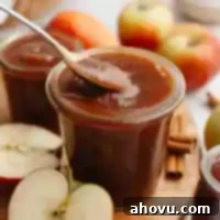 Homemade Spiced Apple Butter 12 A jar of apple butter with a spoon being dipped into it.