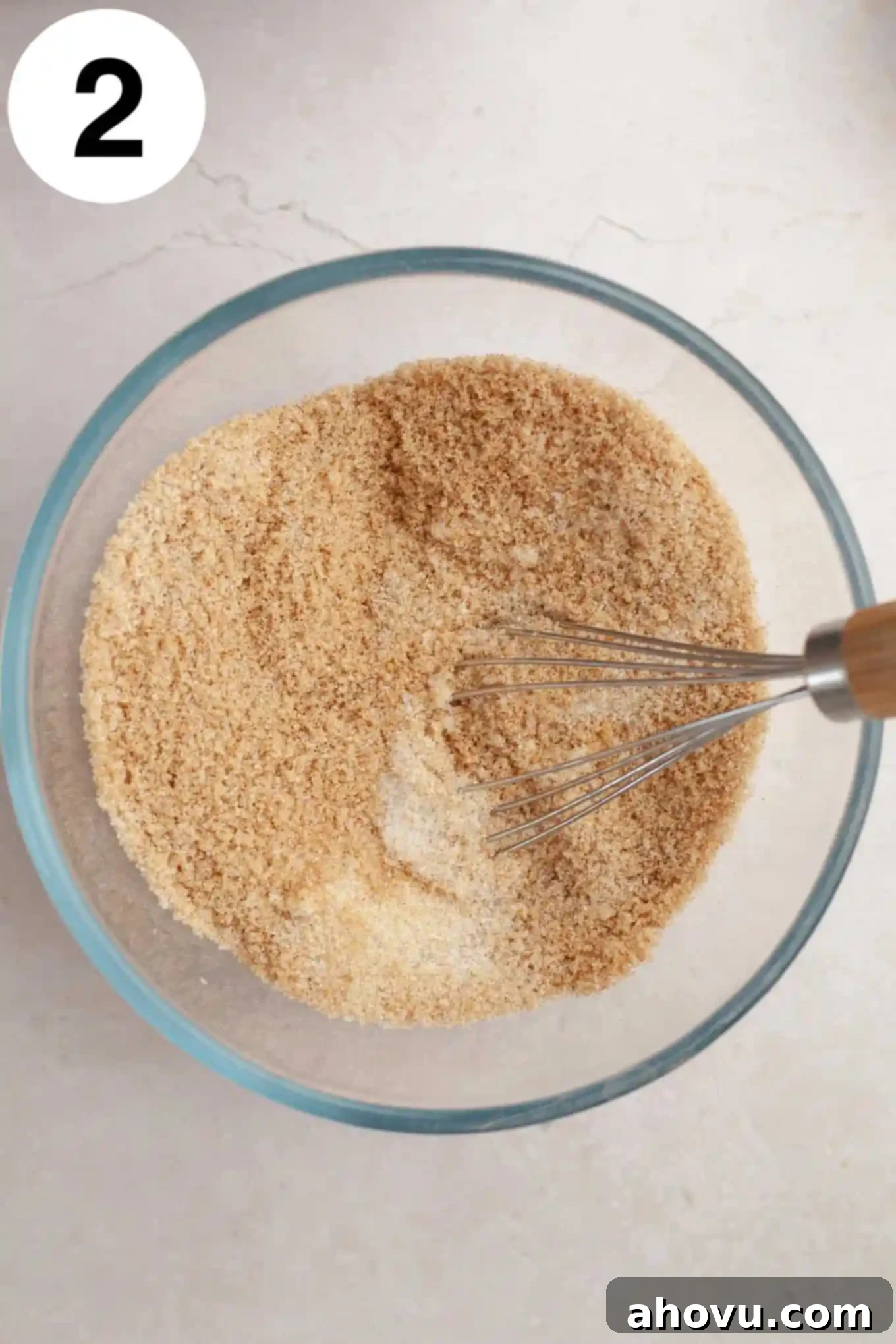 Homemade Spiced Apple Butter 5 A close-up overhead view of a glass mixing bowl containing a mixture of brown sugar, granulated sugar, cinnamon, nutmeg, and a whisk, ready to be combined for the apple butter recipe.