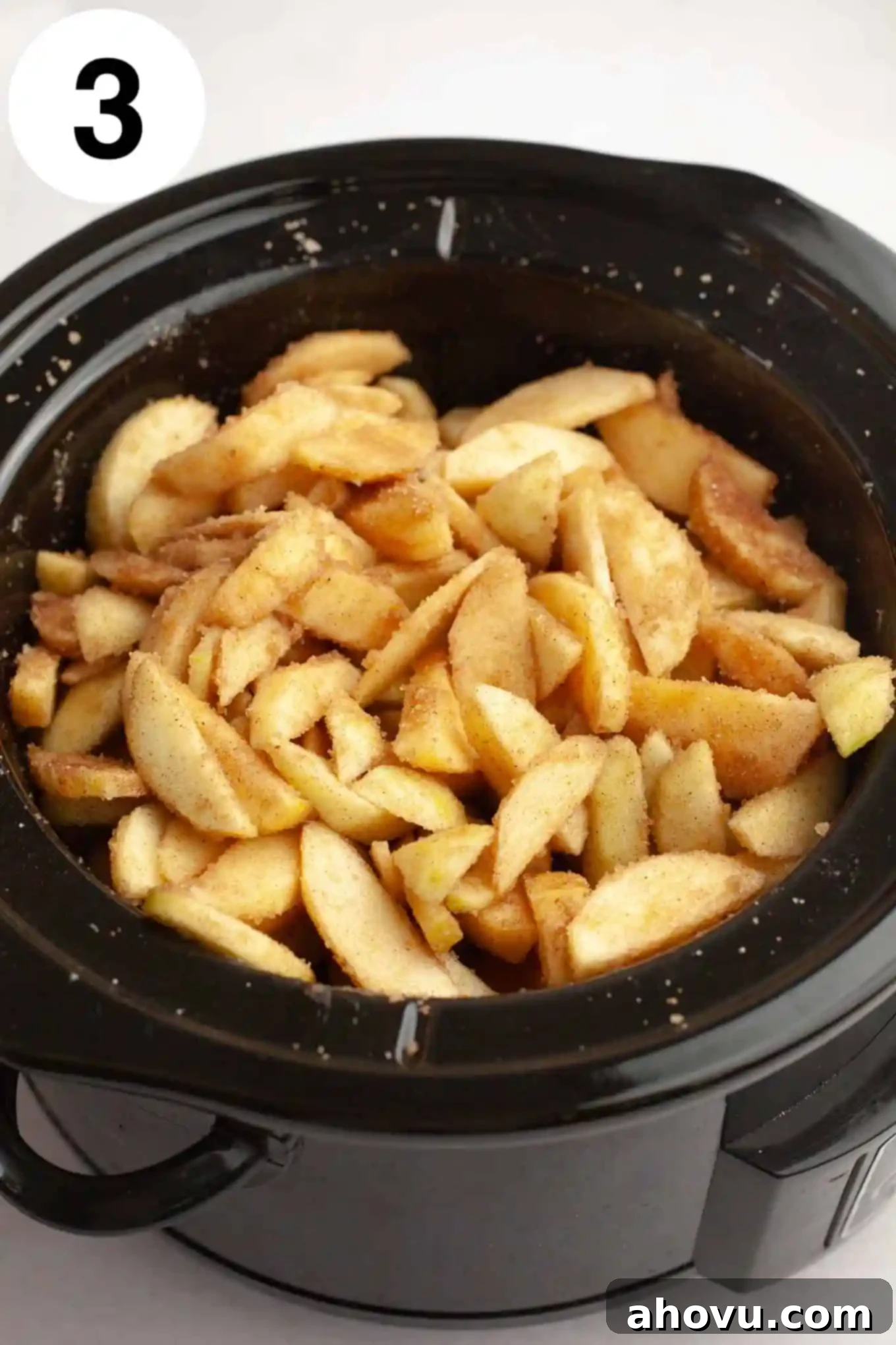 Homemade Spiced Apple Butter 6 An overhead view of sliced apples covered in a brown sugar and spice mixture, ready to be cooked in a Crockpot.