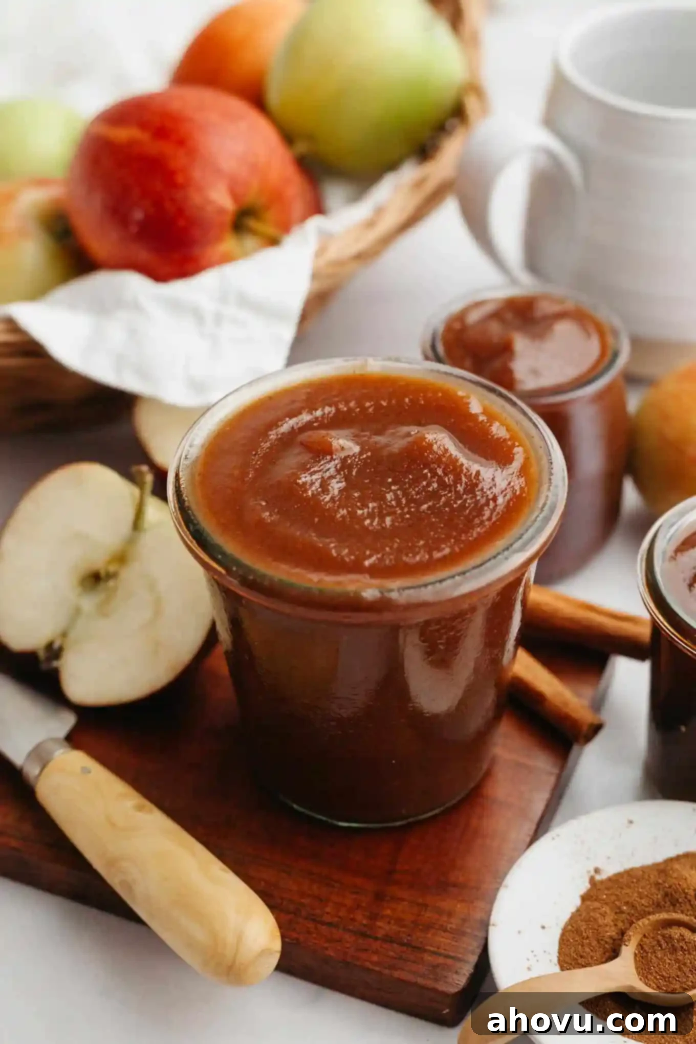 Homemade Spiced Apple Butter 10 A beautifully styled jar of homemade apple butter sits on a wooden cutting board, surrounded by fresh apples, cinnamon sticks, and star anise, creating an inviting rustic scene.