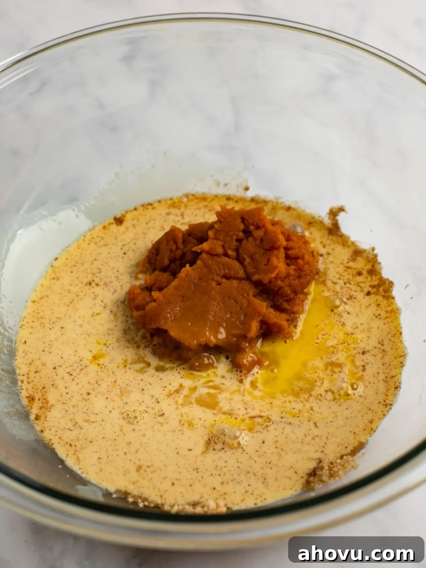 The ingredients for the pumpkin pie filling in a glass mixing bowl.