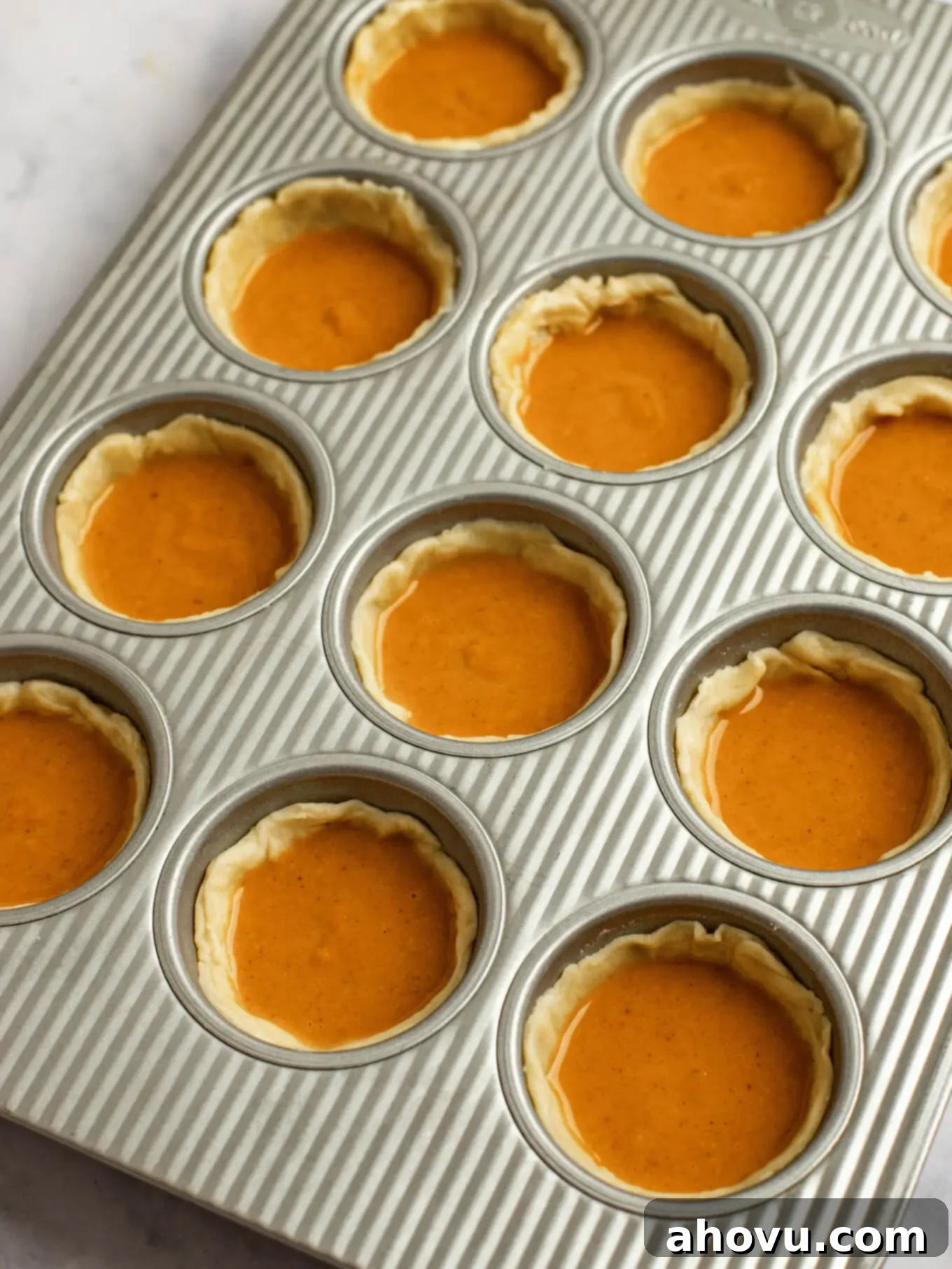 Pumpkin pie filling added to the pie crusts in the muffin pan.