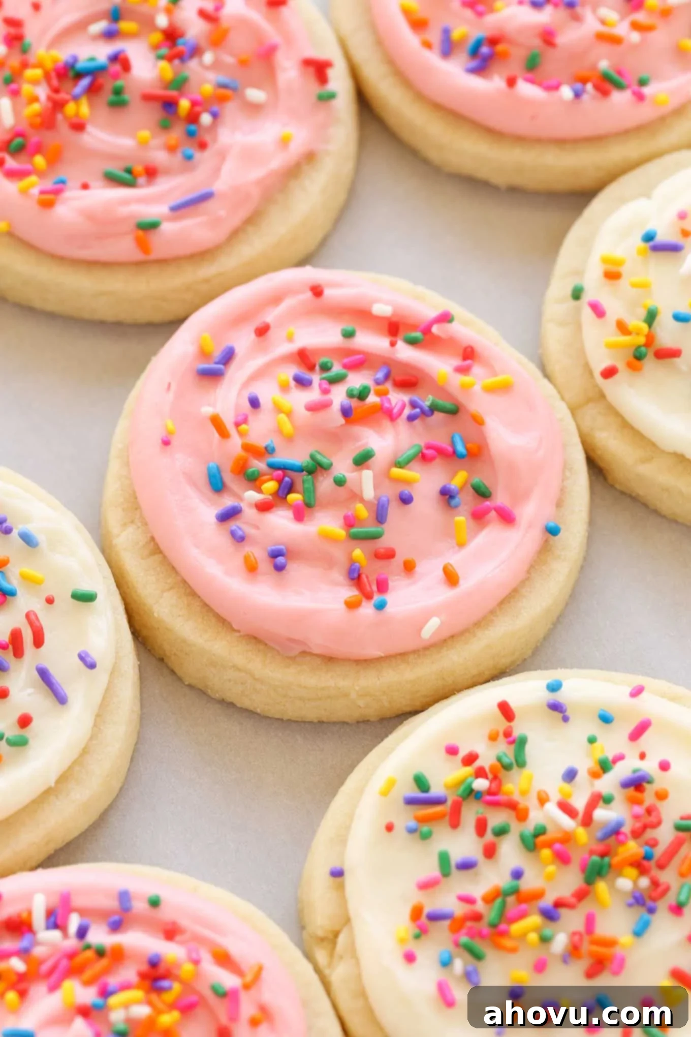 Overhead view of soft frosted sugar cookies topped with rainbow sprinkles. 