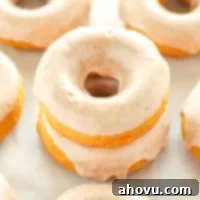 A stack of two baked pumpkin donuts with maple cinnamon glaze.