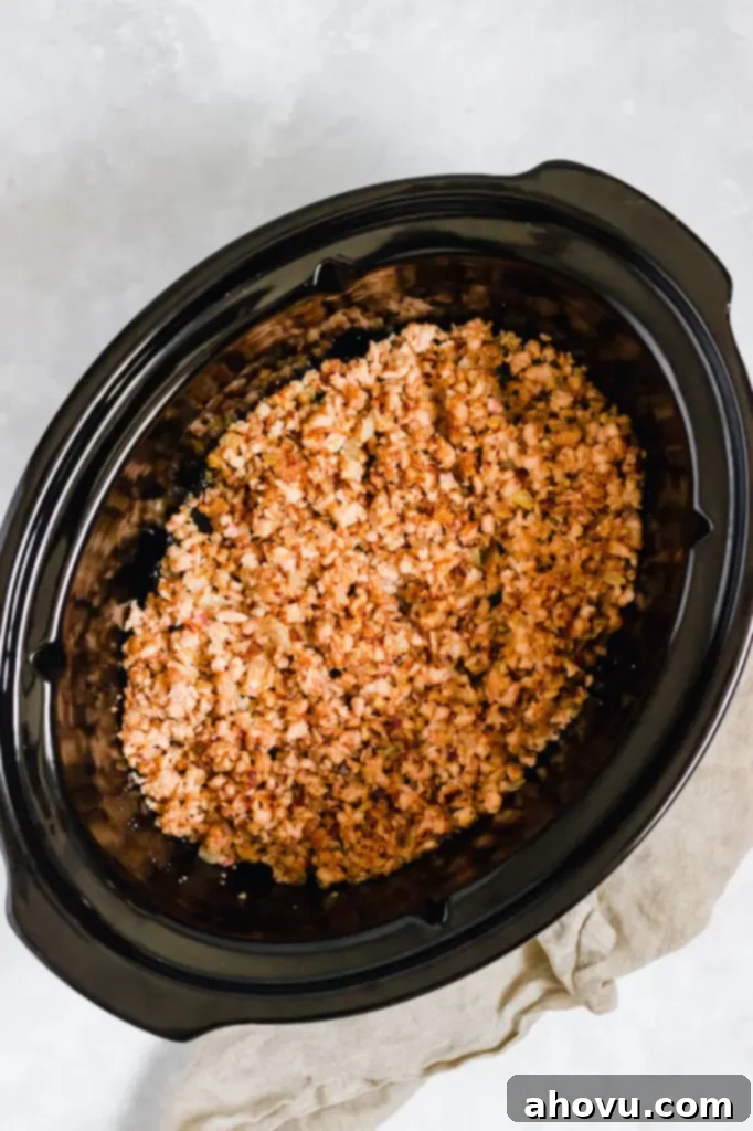 A crockpot filled with cooked ground turkey and onions.
