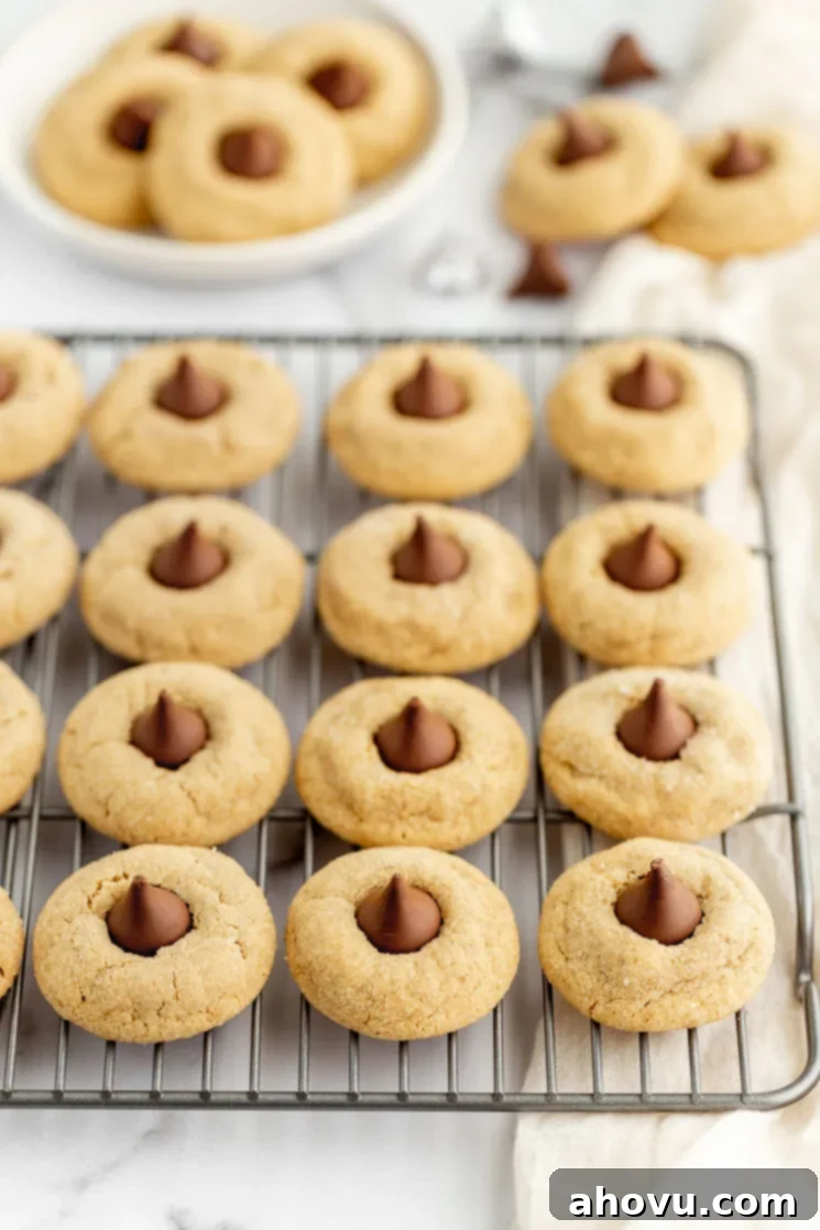 Grandma's Peanut Butter Blossoms 5 A cooling rack holding peanut butter blossoms with more in the background on a plate and napkin.