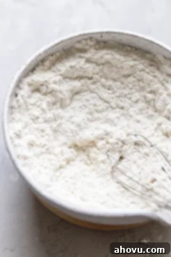 The dry ingredients for cookies, including flour, baking powder, and salt, resting in a speckled white mixing bowl.