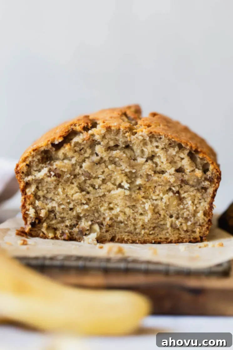 A straight on shot of a loaf of banana bread with the end cut off to show the texture. The bread is golden brown with a soft, moist interior, suggesting it's perfectly baked. This image highlights the inviting texture and deliciousness of the homemade banana bread.