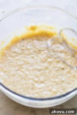 A glass bowl with the wet ingredients for banana bread mixed together. This shows the creamy, combined texture of butter, sugars, eggs, and vanilla before the dry ingredients are added.