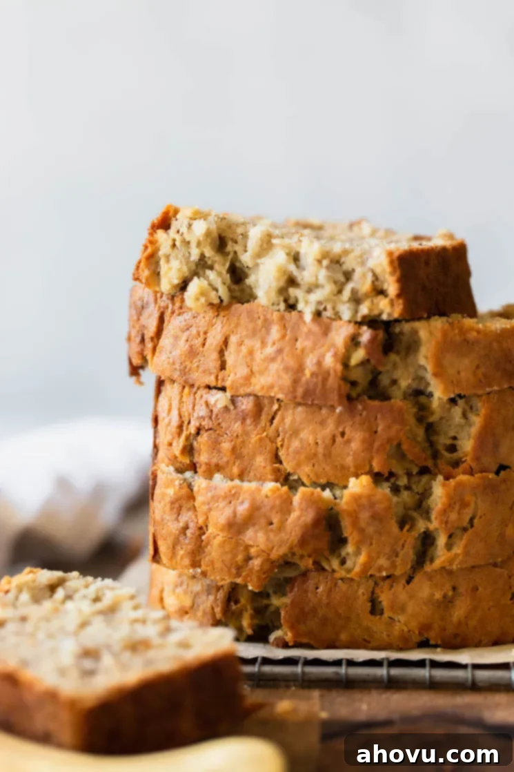 A stack of banana bread slices on top of an antique cooling rack. The slices are thick and inviting, showing off the perfectly baked texture.