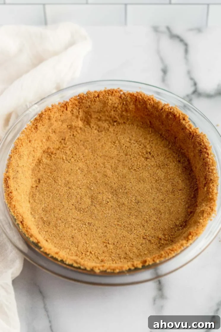 Perfect Homemade Graham Cracker Crust 2 A beautifully baked golden graham cracker crust nestled in a clear glass pie dish, ready for filling.