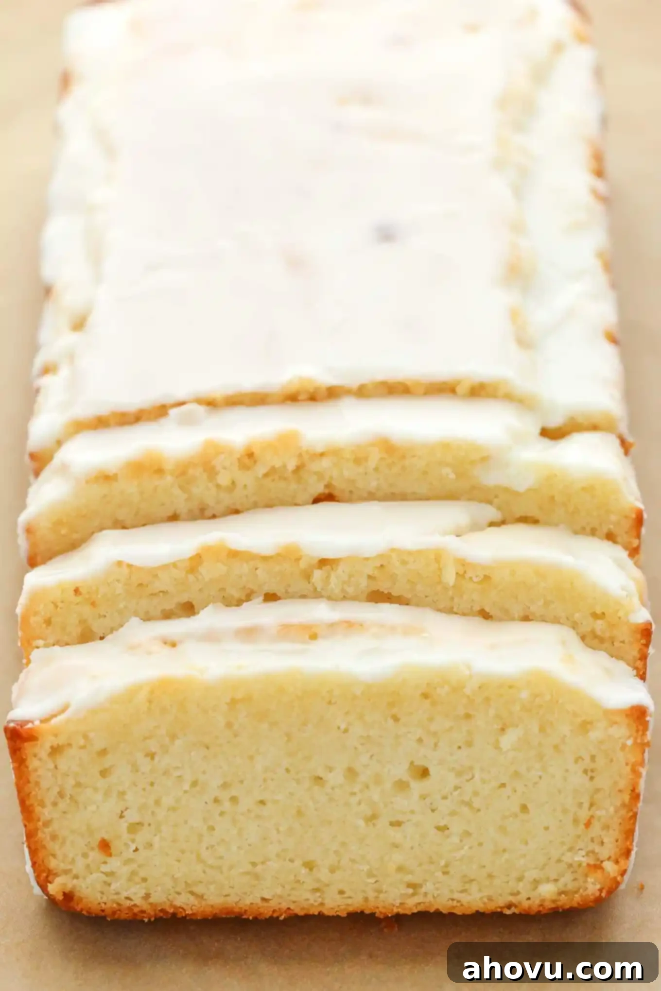 A loaf of lemon bread with glaze on top. Three slices have been cut from the front. 