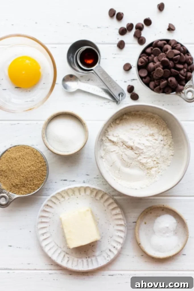 Irresistible Small Batch Chocolate Chip Cookies 3 The ingredients needed to make a small batch of chocolate chip cookies sitting on top of a worn white surface.