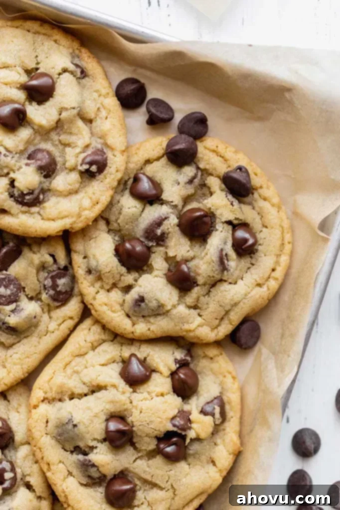 Irresistible Small Batch Chocolate Chip Cookies 5 A close up image of chocolate chip cookies on a baking sheet lined with brown parchment paper.
