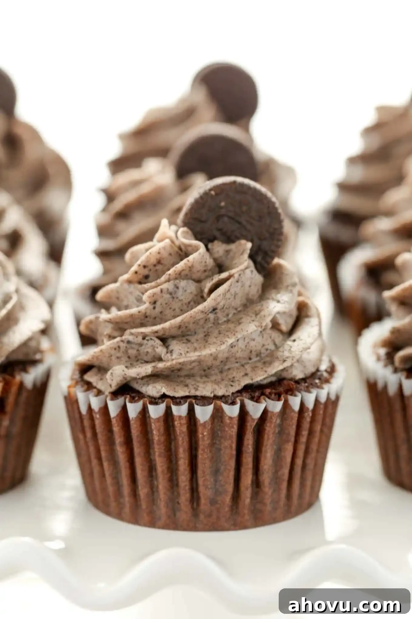 Three rows of Oreo cupcakes on a white cake stand. 