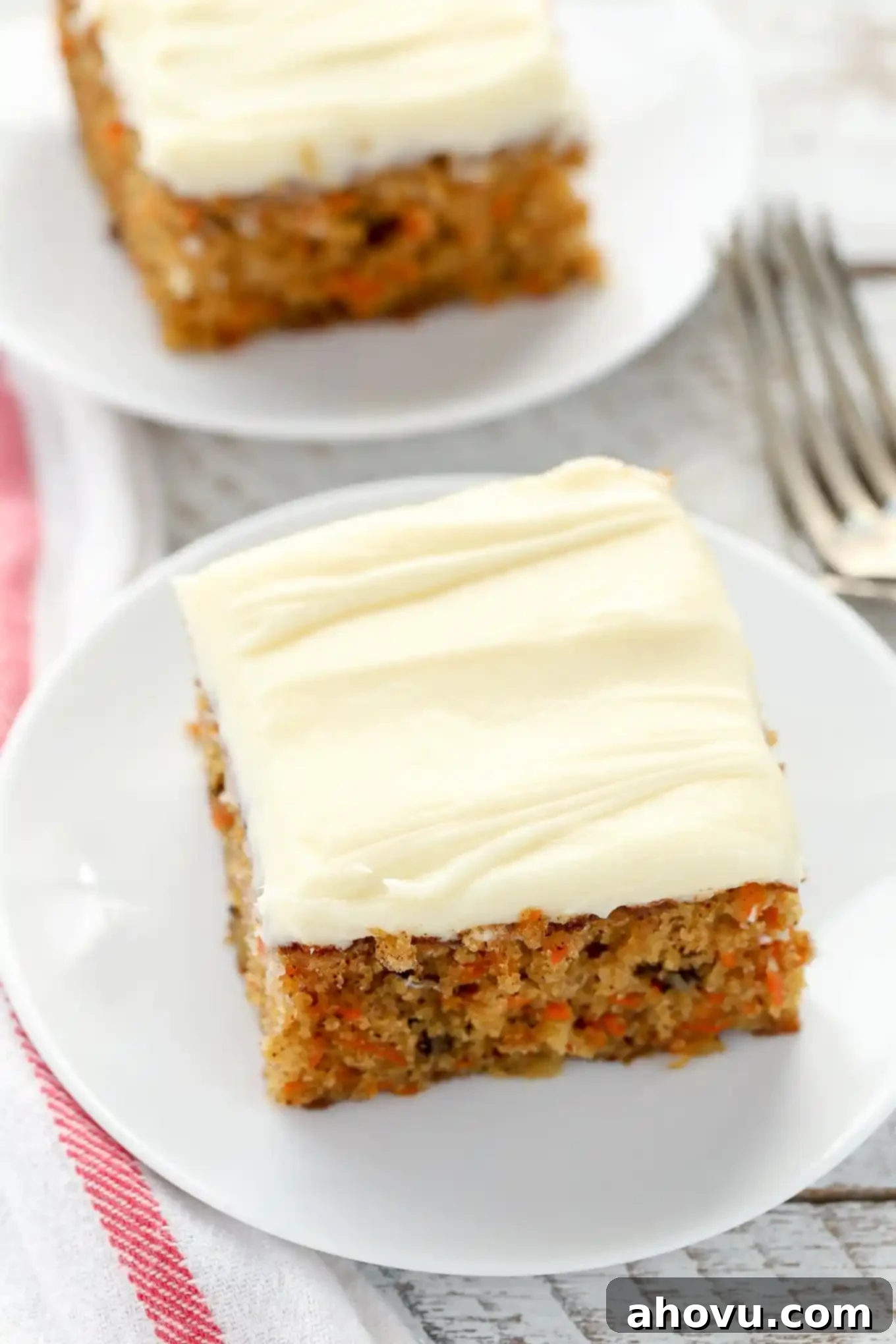 Sun-Kissed Pineapple Carrot Cake 2 Two slices of moist pineapple carrot cake on white plates, showcasing the rich texture and delicious frosting.