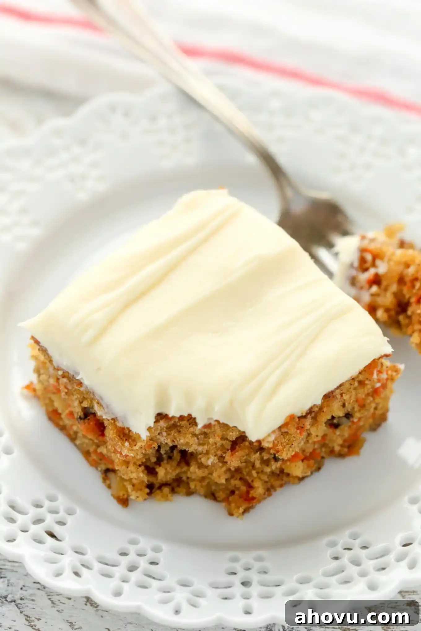 Sun-Kissed Pineapple Carrot Cake 5 A slice of pineapple carrot cake on a white plate with a fork, ready to be enjoyed.
