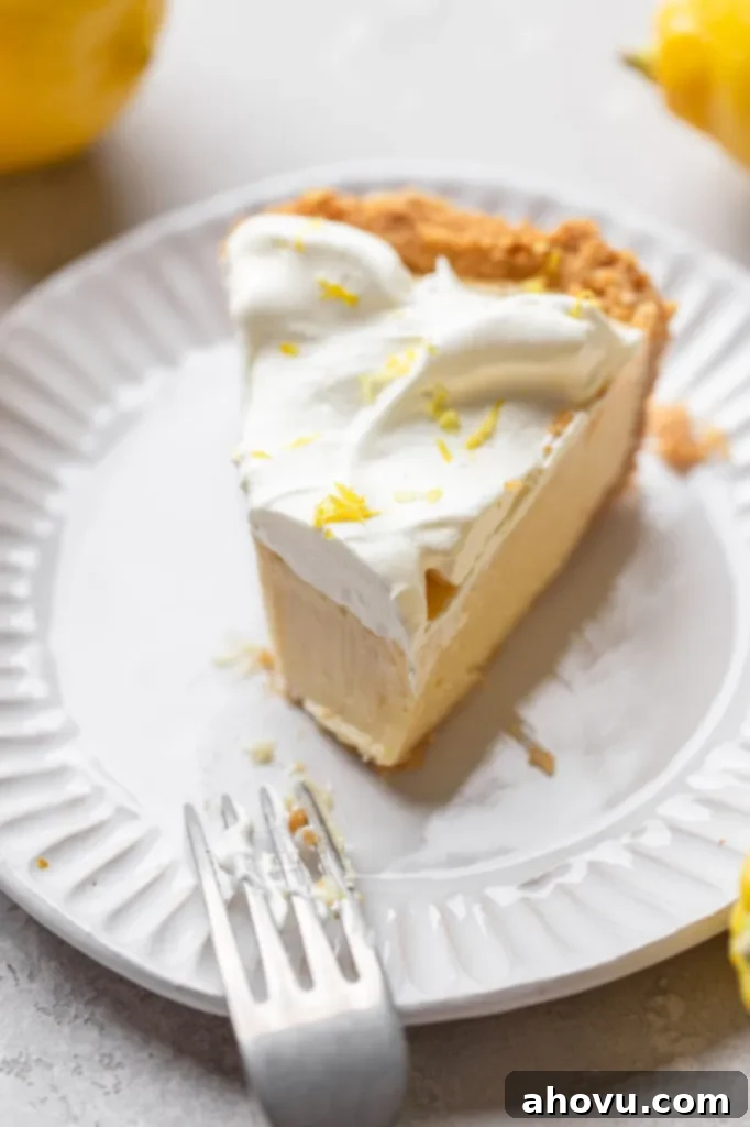 Golden Citrus Dream 6 A single slice of lemon pie on a white plate with a bite taken out.