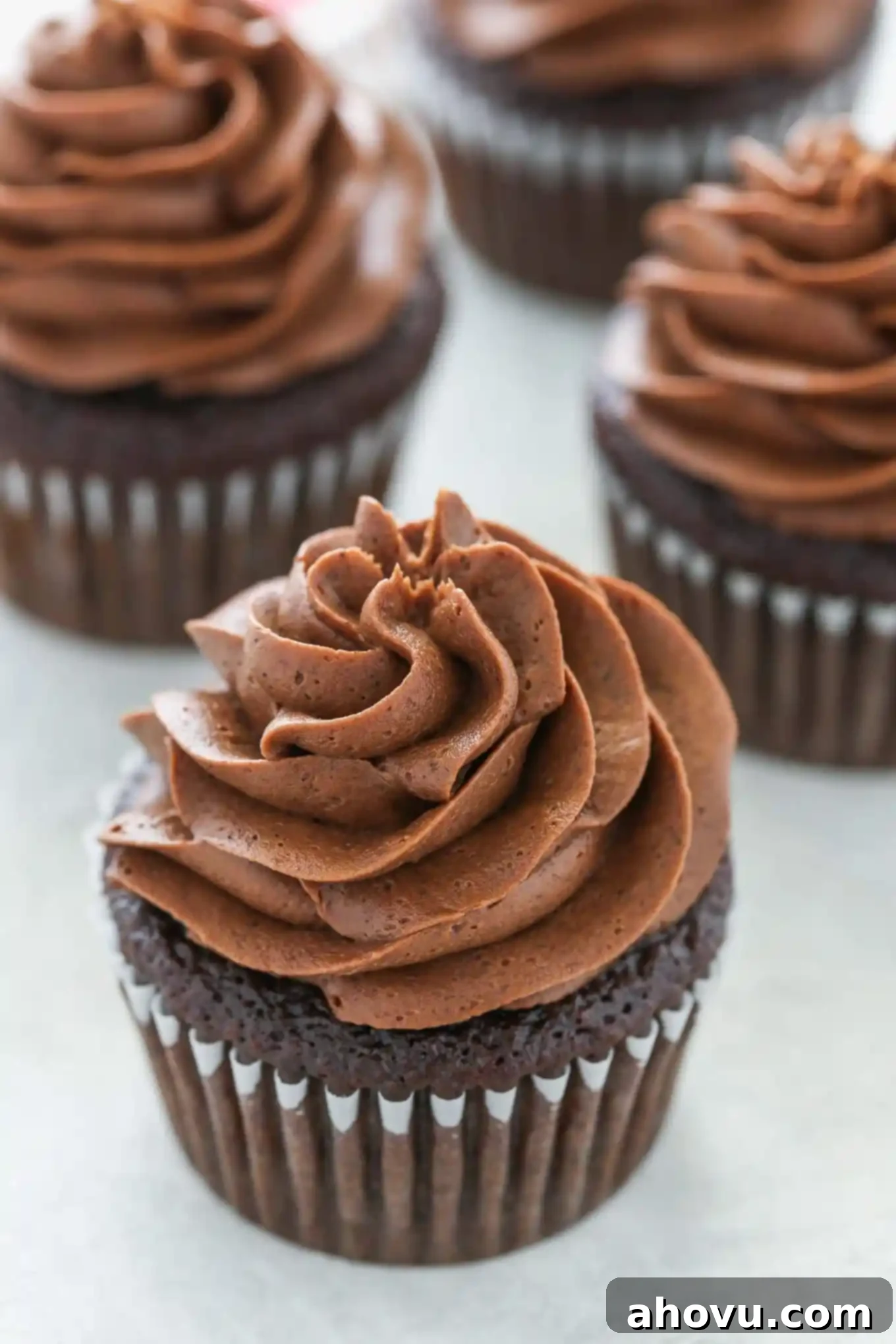 Decadent Chocolate Buttercream 4 Four chocolate cupcakes topped with generous swirls of homemade chocolate frosting, ready to be enjoyed.