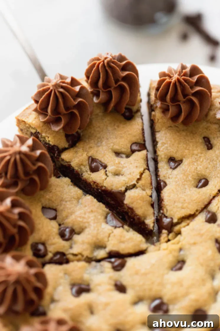 A chocolate chip cookie cake beautifully cut into individual slices, with one slice being carefully removed using a cake server.