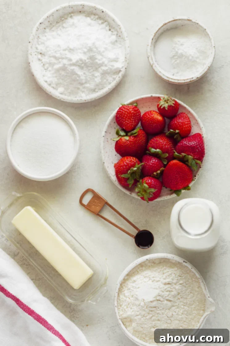 Several of the essential ingredients, including fresh strawberries, flour, and butter, artfully arranged on a gray surface, ready for making strawberry shortcake.