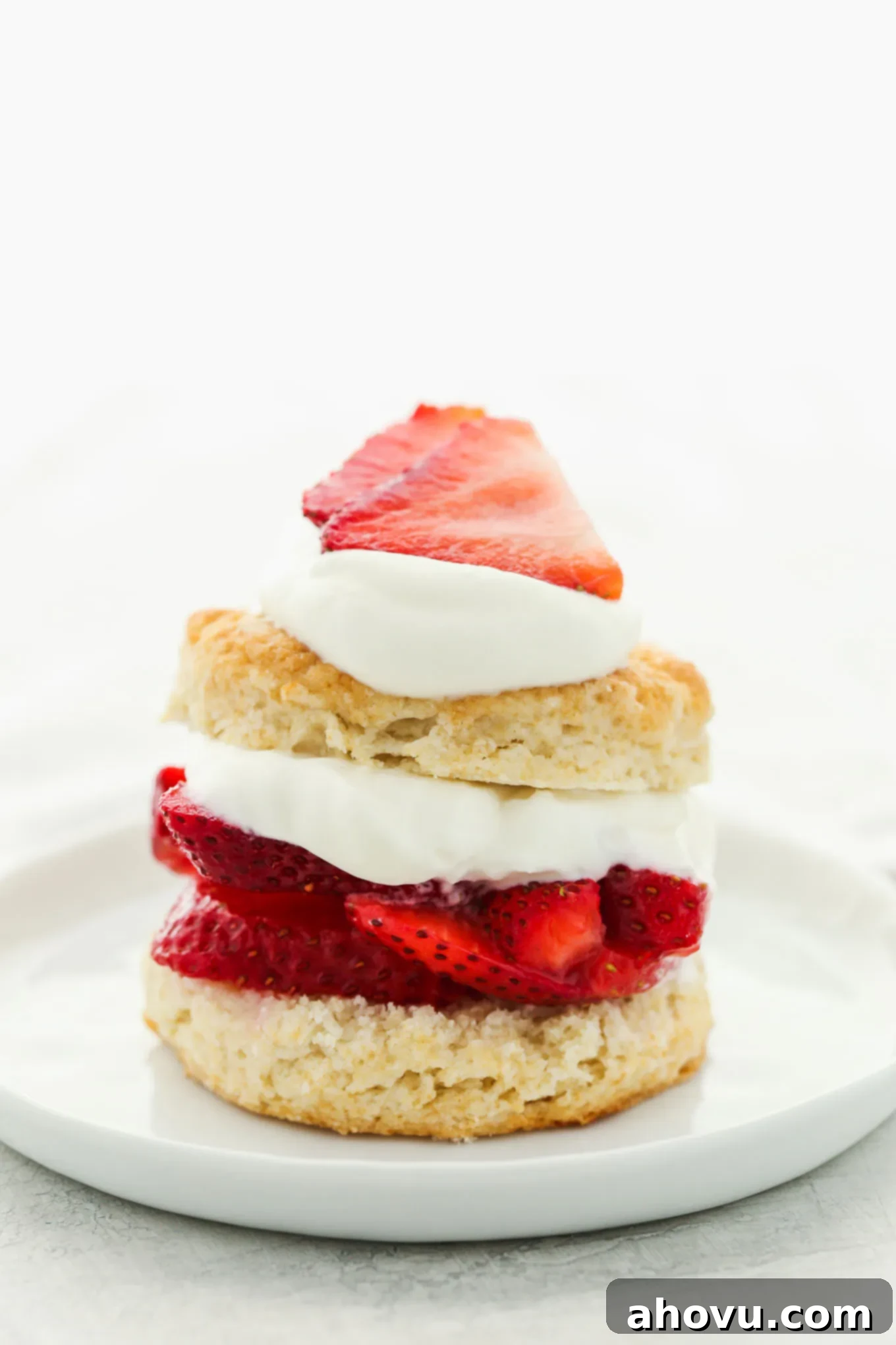A captivating close-up image revealing the delicious layers of a strawberry shortcake on a white plate, highlighting the biscuit, juicy berries, and rich whipped cream.