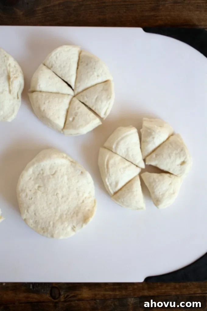 Overhead view of raw biscuit dough on a cutting board. 