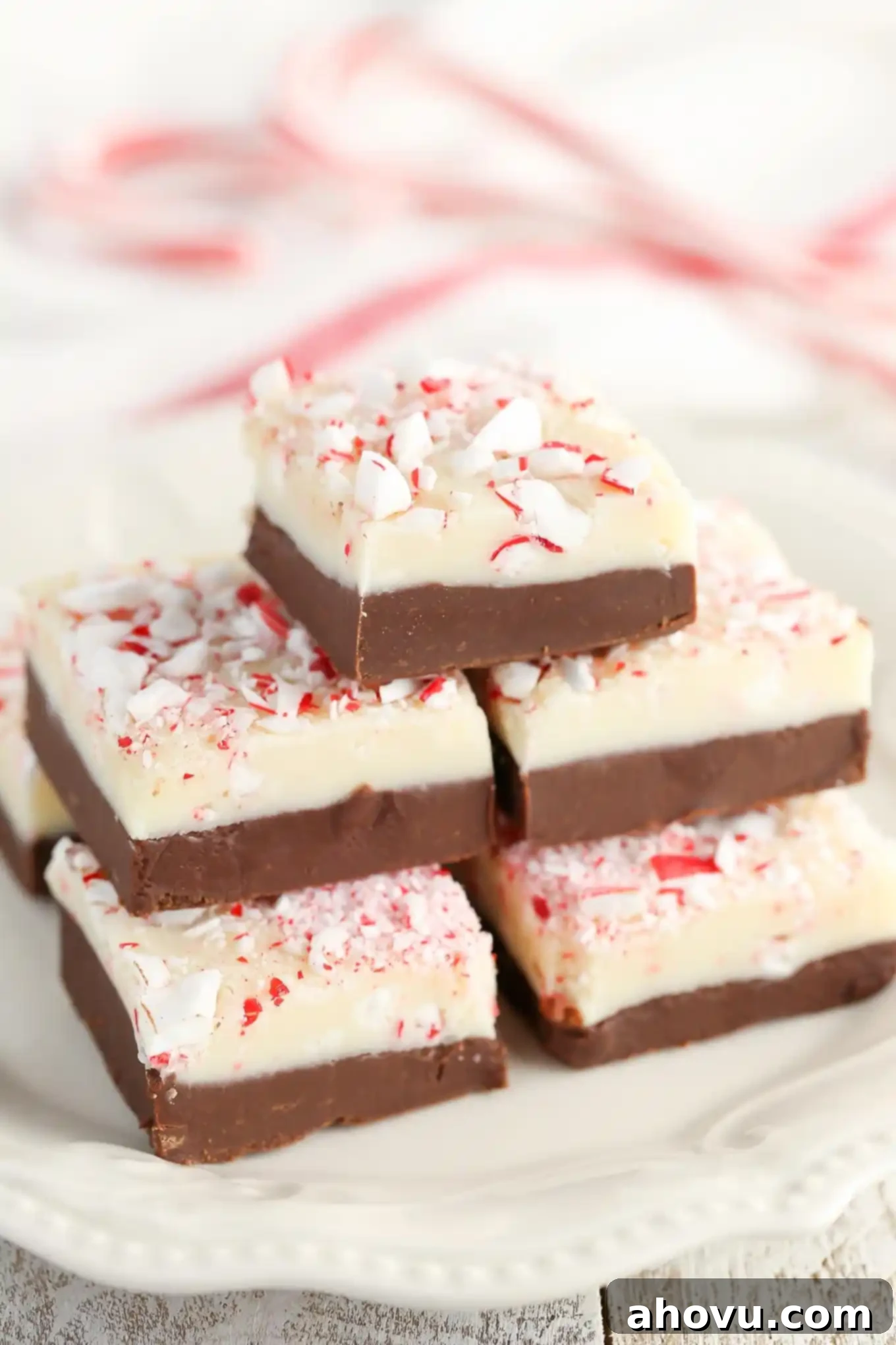 Stack of festive peppermint fudge squares on a white plate, ready to be served during Christmas holidays.