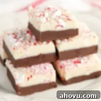A top-down shot of a block of two-layered peppermint fudge with crushed candy canes on top, in an 8-inch pan.
