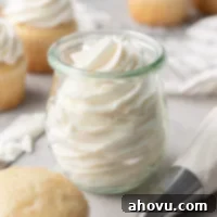 A glass jar filled with gelatin whipping cream. Vanilla cupcakes surround the jar.